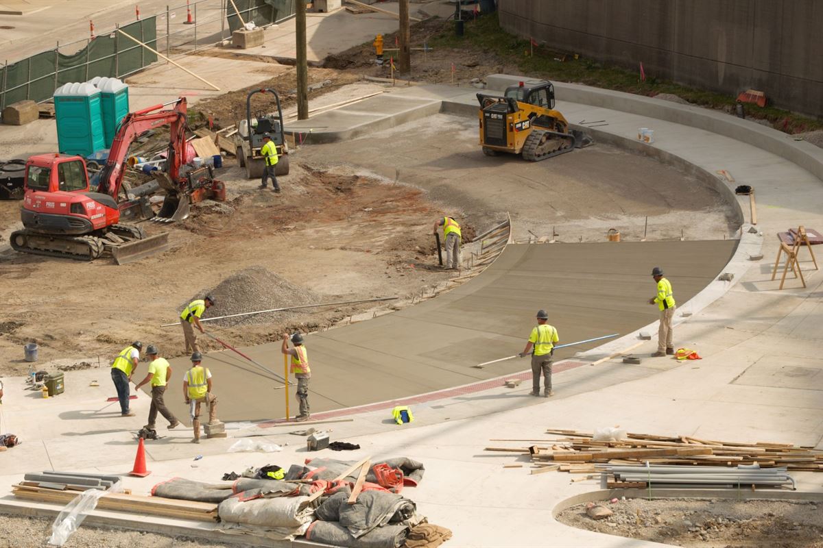 Crew placing concrete paving and curbing on a commercial site