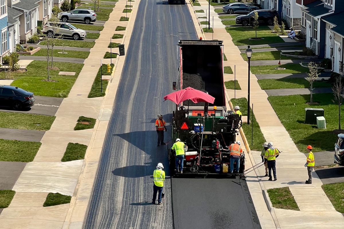 Crew paving a new residential street lined with curb and sidewalks
