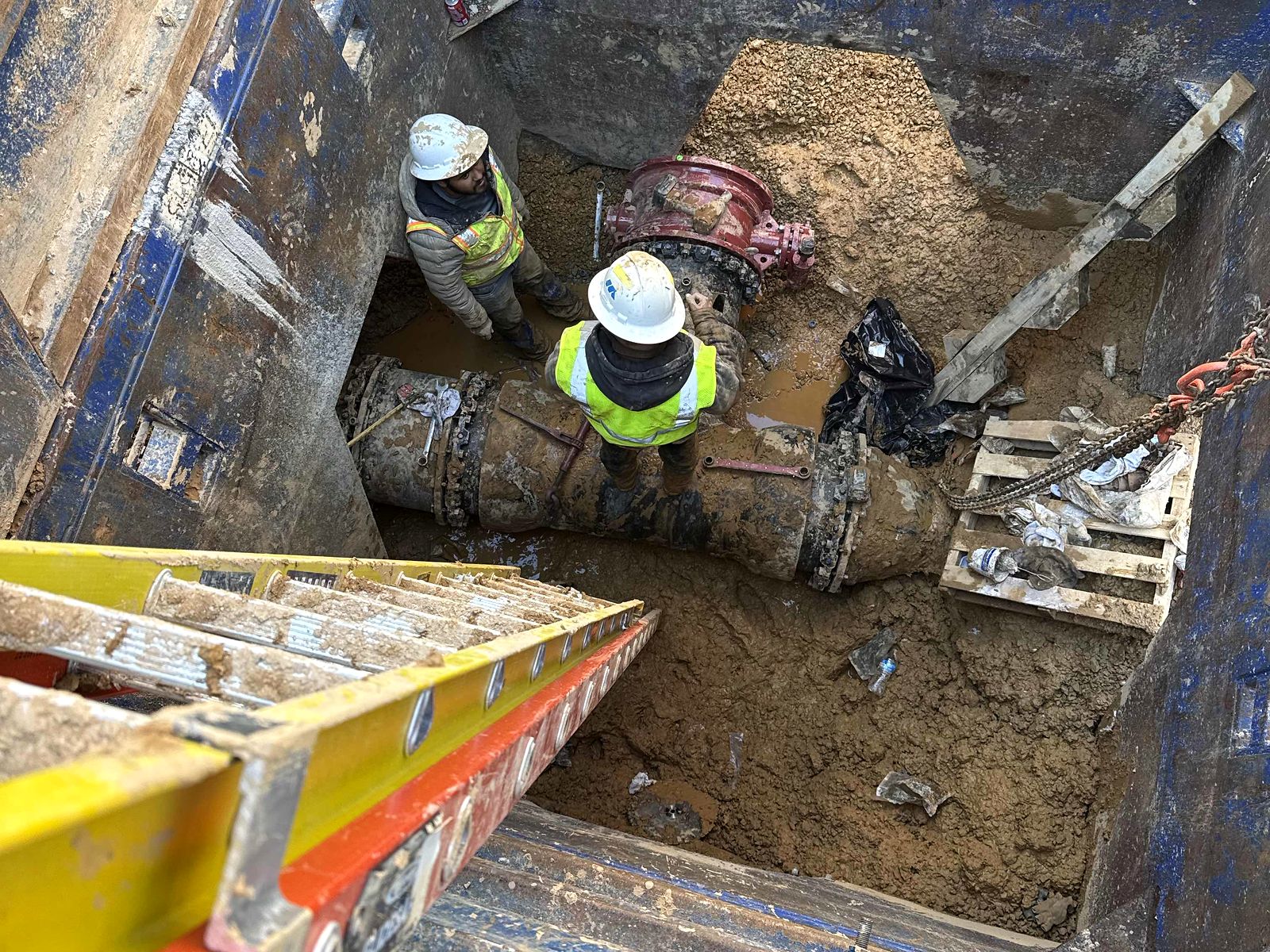 Two crew members connecting a valve on a large water line inside a trench box in Bartow County, Georgia
