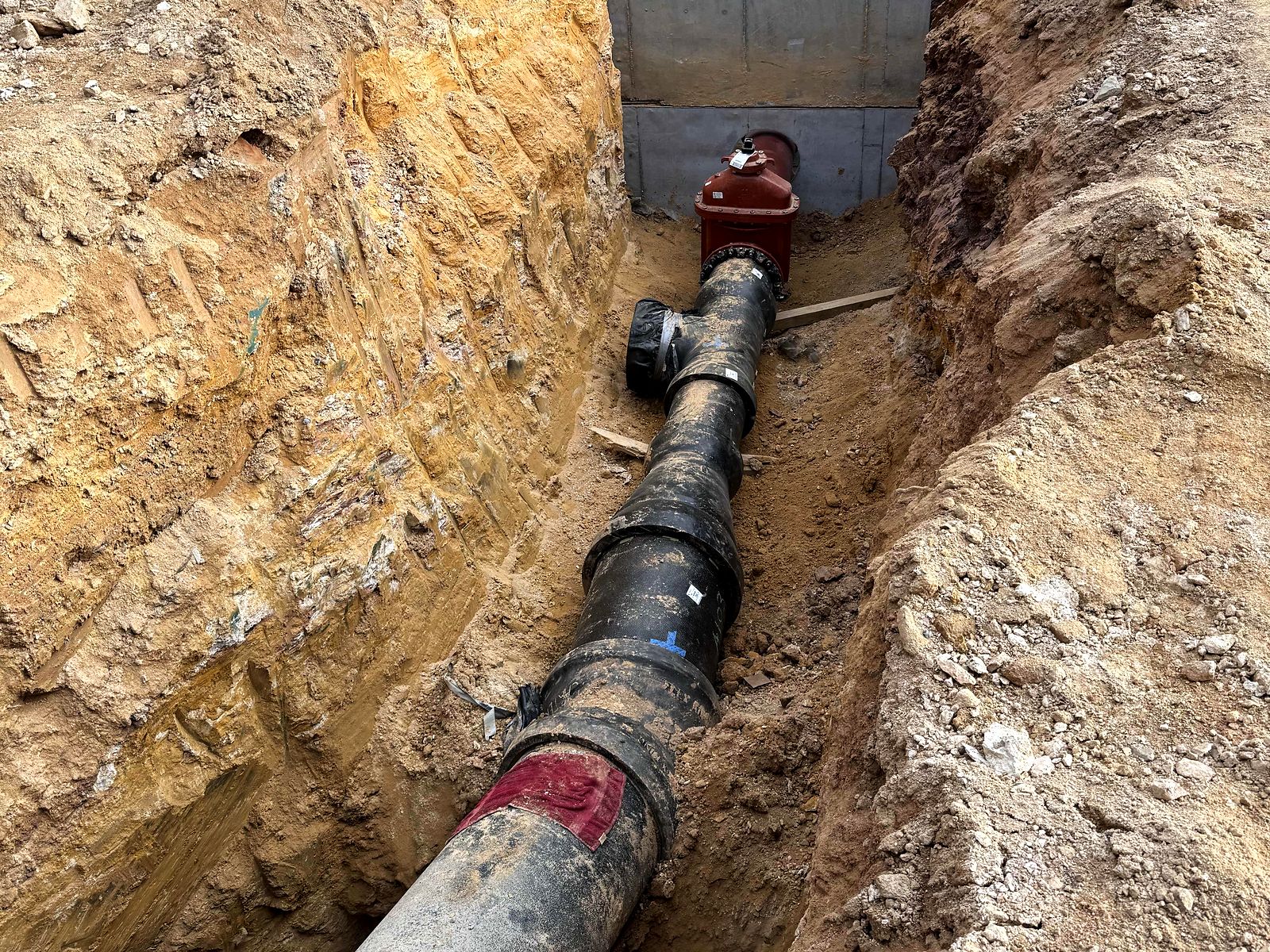 Ductile iron water line and red gate valve in a trench leading to a precast vault in Bartow County, Georgia