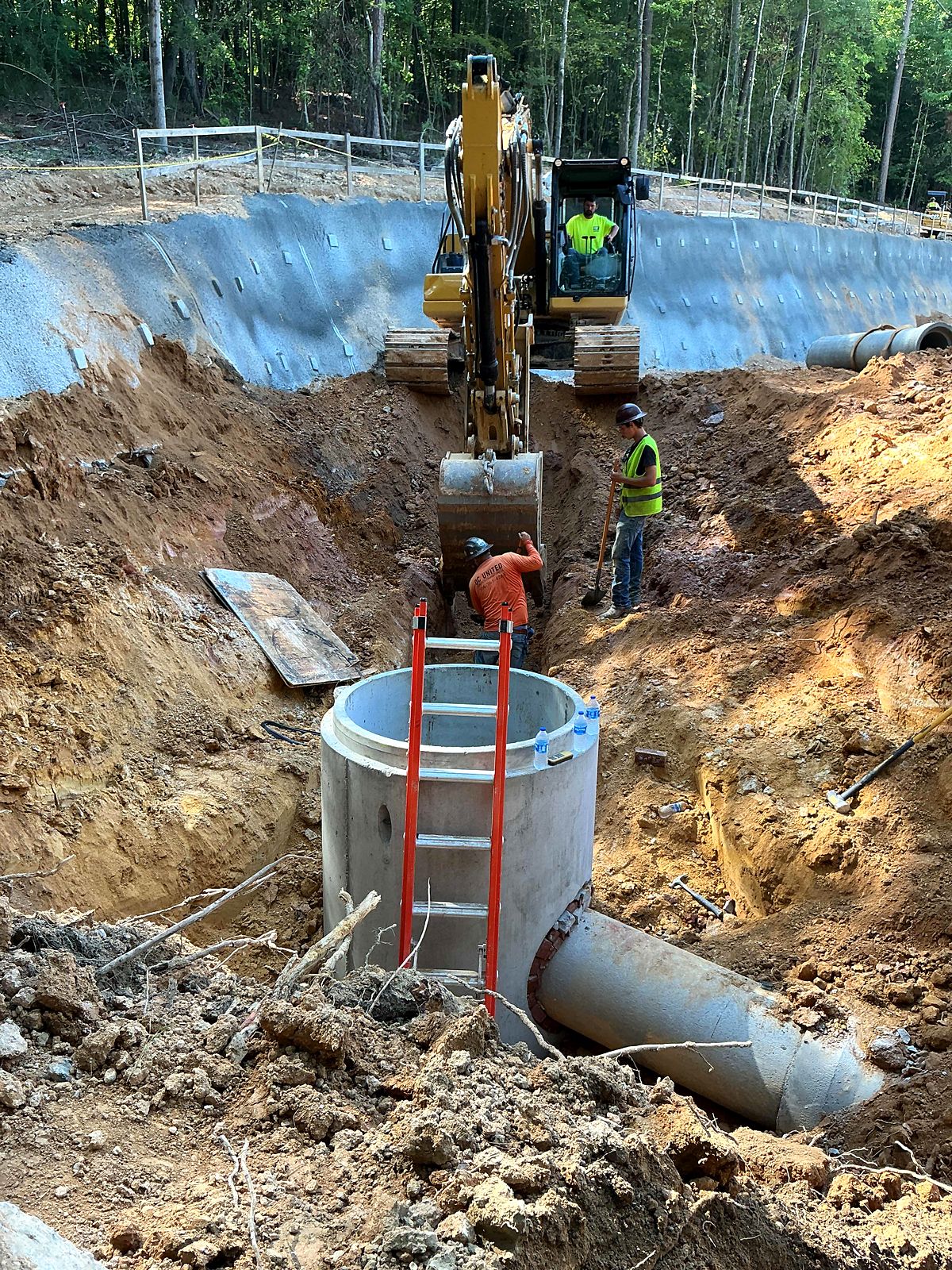 Crew setting a precast manhole on a large pipe in a trench at the pump station site in Bartow County, Georgia