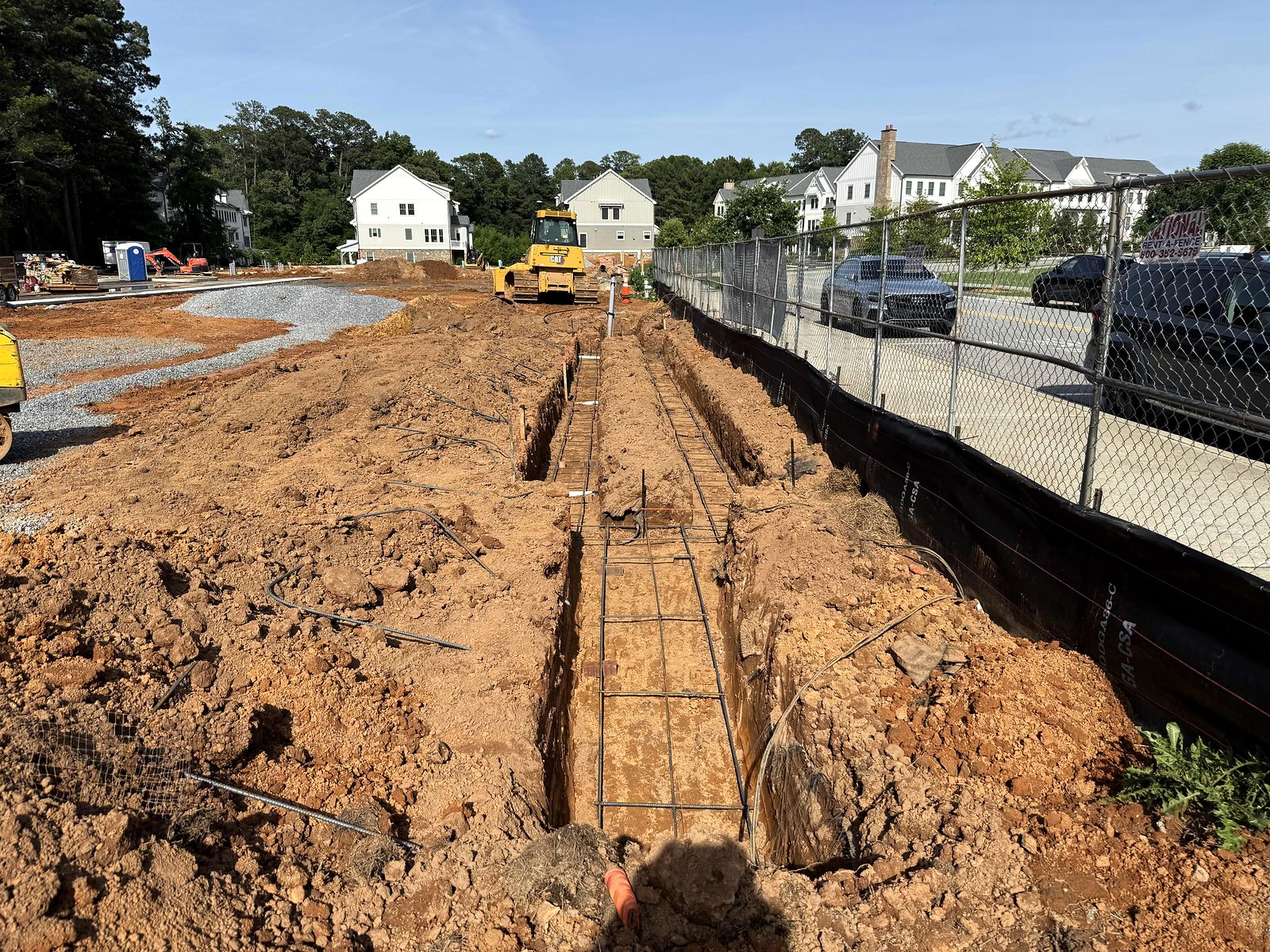 Rebar set in a long footing trench along the site fence at Reliant Market District
