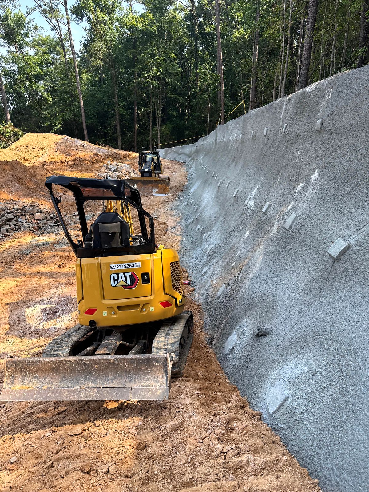 Compact excavator in the excavation below a shotcrete-faced wall at the pump station site in Bartow County, Georgia