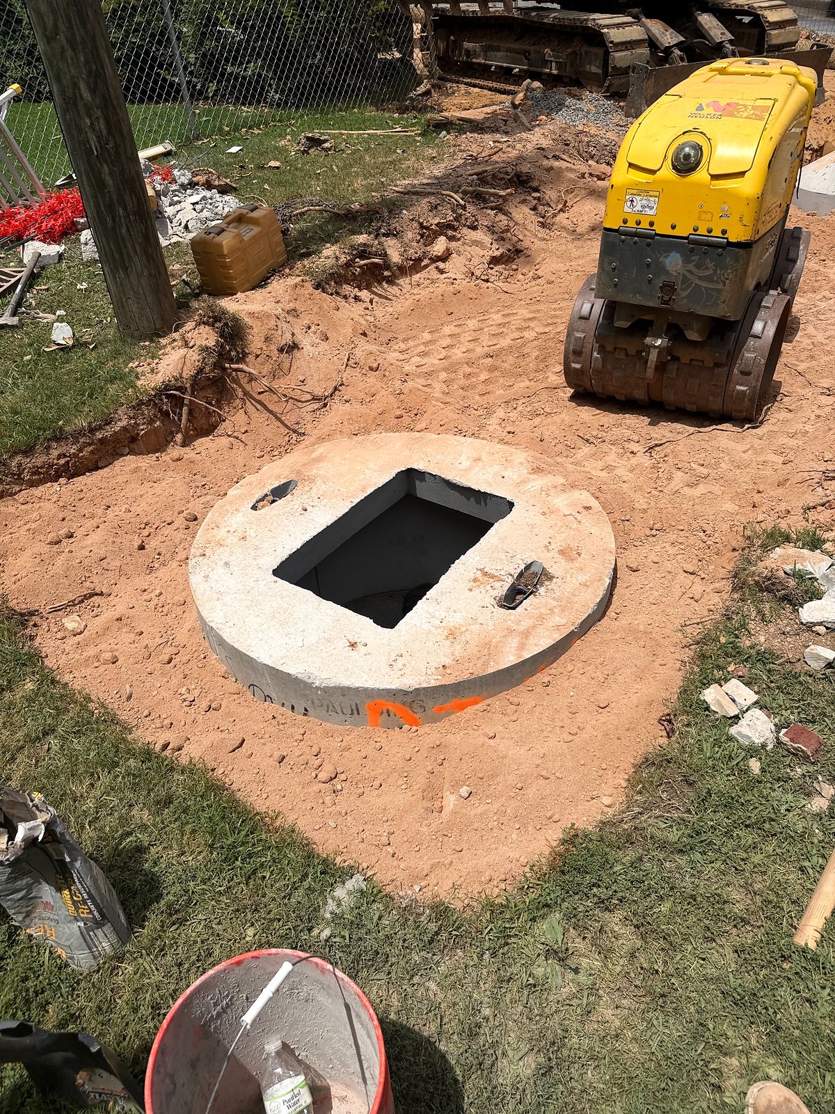 Precast manhole top set at grade beside a trench compactor in Alpharetta, Georgia