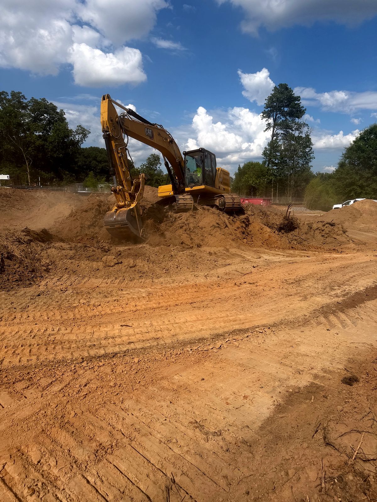 Excavator clearing and stockpiling soil at the start of a commercial site in Alpharetta, Georgia